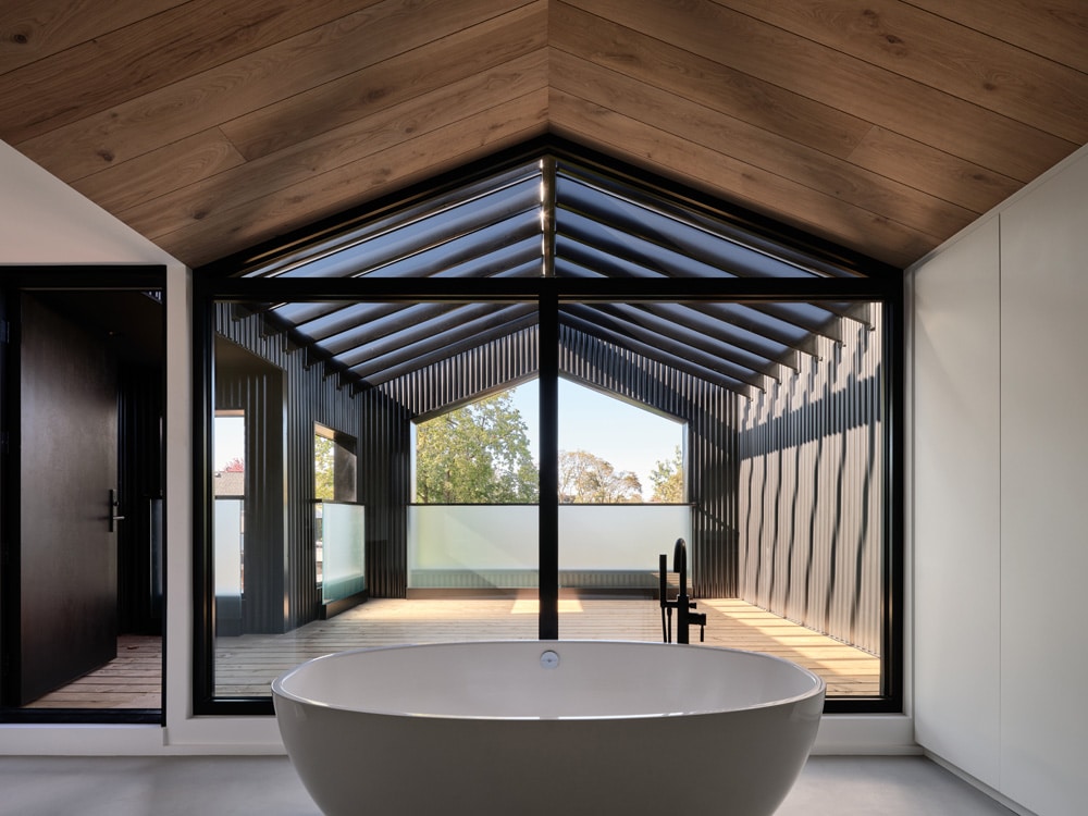 Wellness-Bereich mit frei stehender Badewanne, im Hintergrund eine überdachte Terrasse, Foto: Doublespace Photography