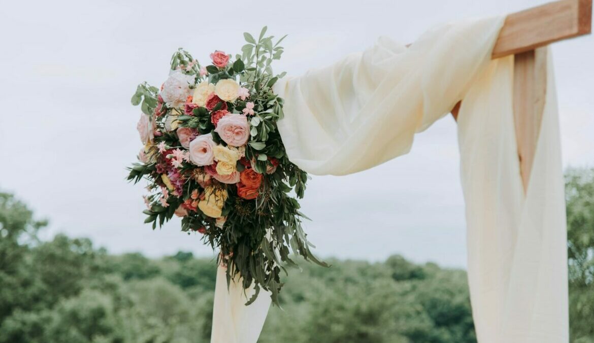 bouquet of assorted-color flowers hanged on brown plank with white textile