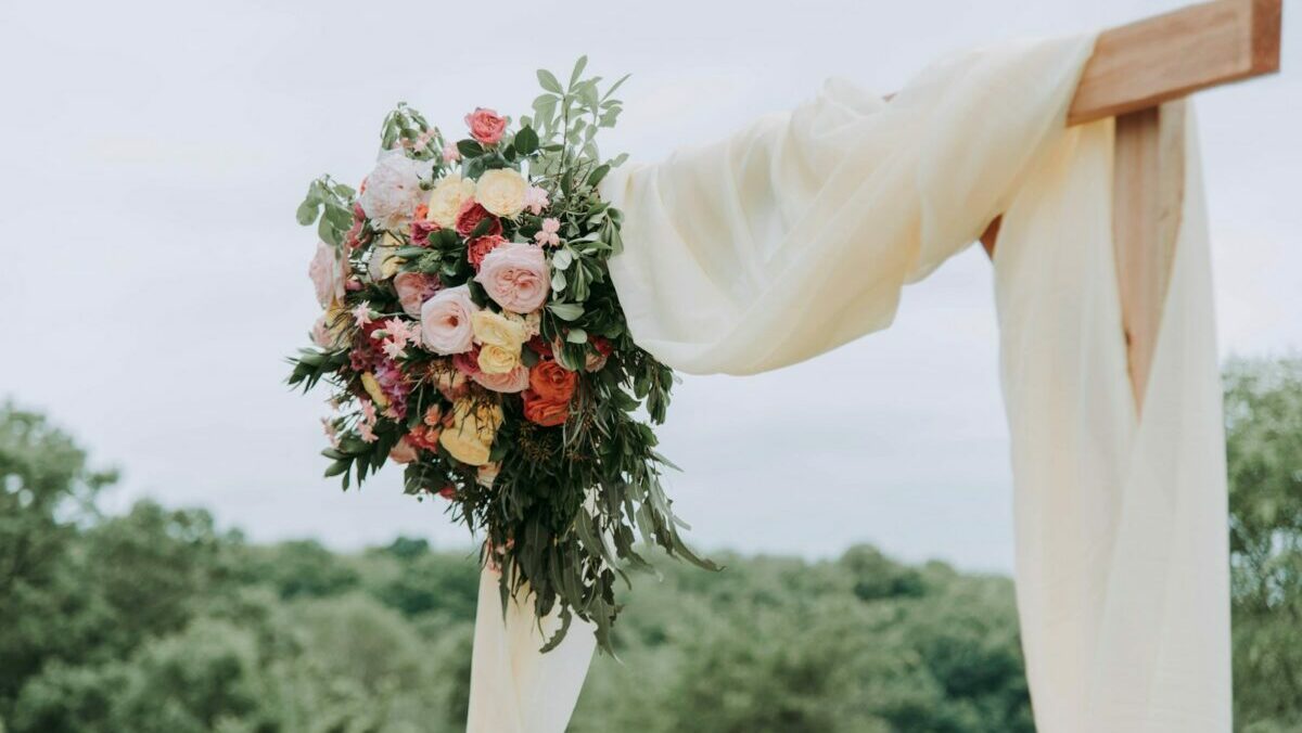 bouquet of assorted-color flowers hanged on brown plank with white textile