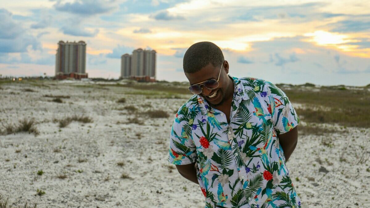 smiling man wearing floral dress shirt standing on the grass field