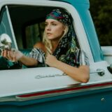 photography of woman holding side mirror in white and green 2-door pickup truck