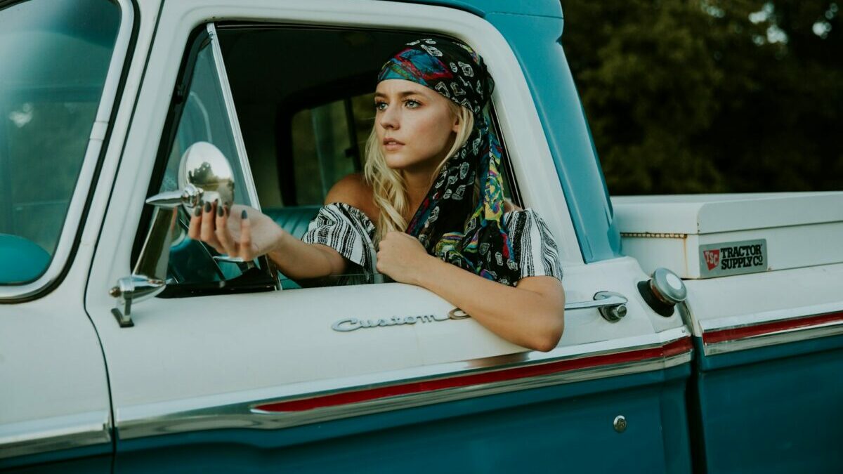 photography of woman holding side mirror in white and green 2-door pickup truck