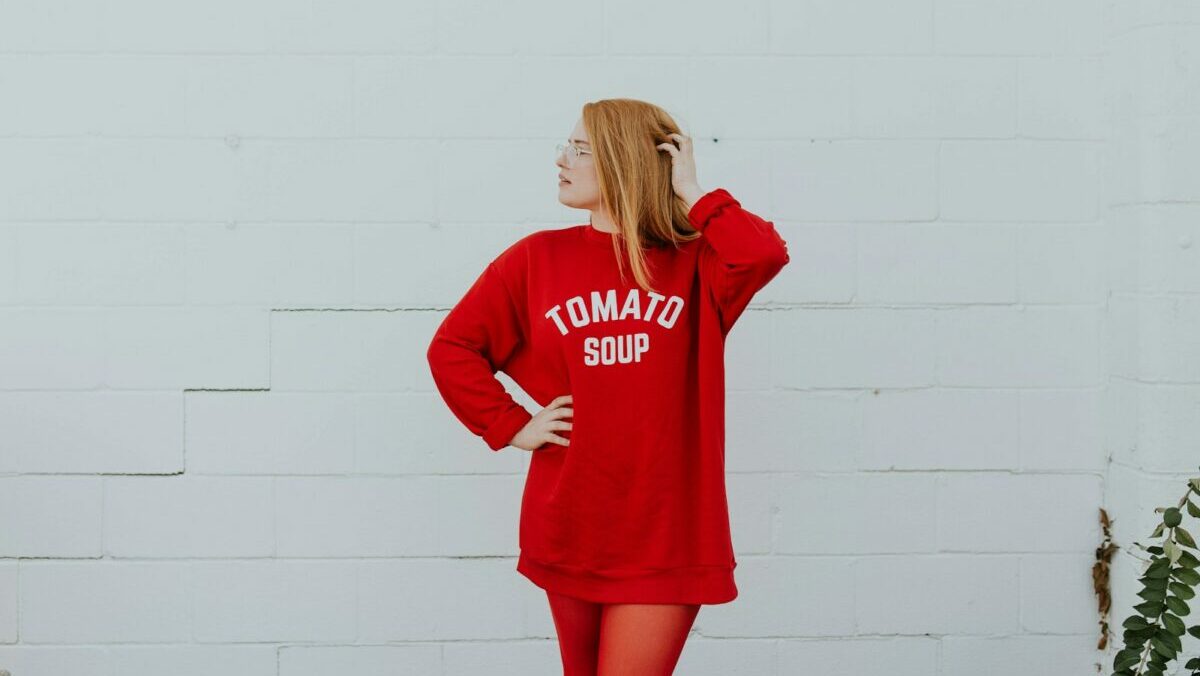 woman wearing red long-sleeved shirt standing near white painted wall