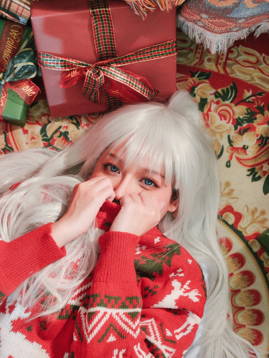 a woman with white hair laying on a bed next to a pile of presents